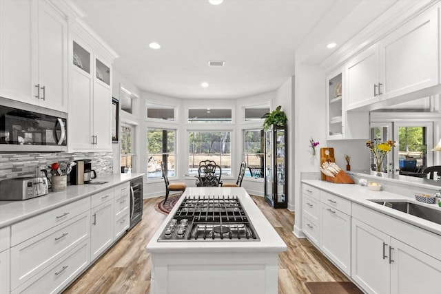 kitchen with white cabinetry, backsplash, stainless steel appliances, and a wealth of natural light