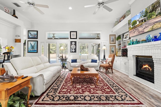 living room with french doors, hardwood / wood-style flooring, a brick fireplace, and crown molding