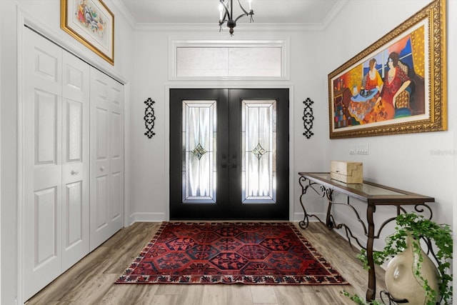 entryway featuring french doors, crown molding, an inviting chandelier, and wood-type flooring