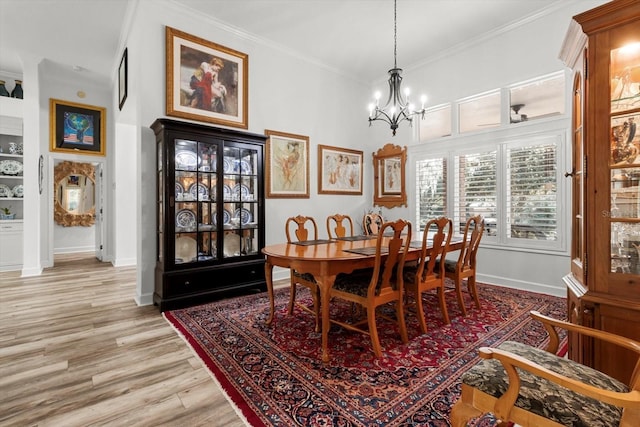 dining room featuring light wood-type flooring, crown molding, and a chandelier