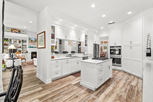 kitchen with light wood-type flooring, white cabinetry, stainless steel appliances, and sink