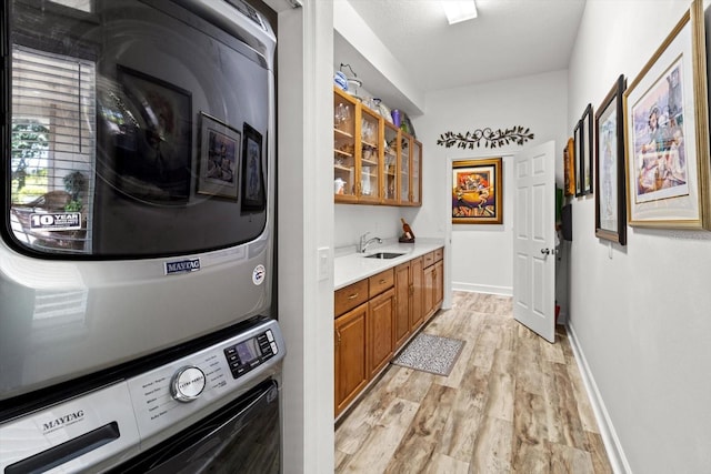 washroom featuring stacked washer and dryer, sink, and light hardwood / wood-style floors