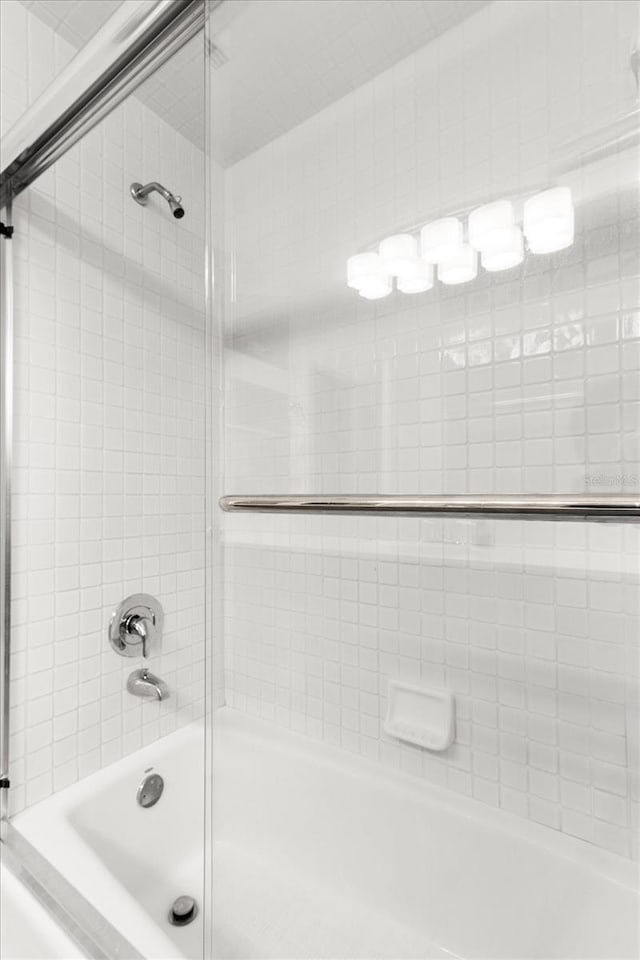 bathroom featuring combined bath / shower with glass door