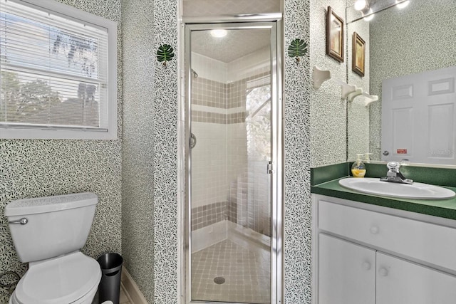 bathroom featuring toilet, vanity, an enclosed shower, and a wealth of natural light