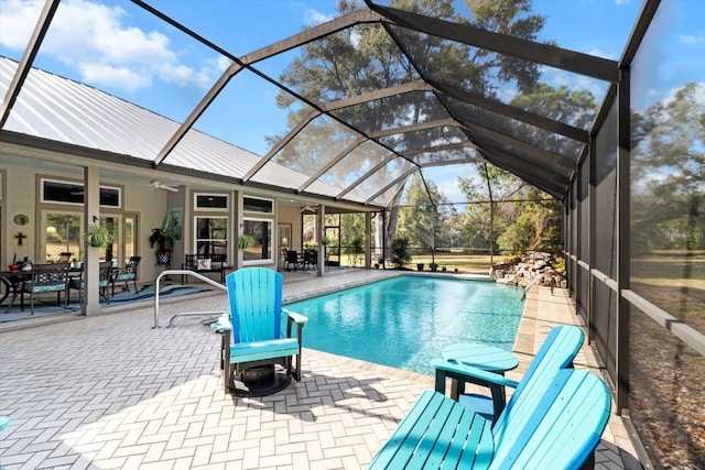 view of swimming pool with ceiling fan, glass enclosure, and a patio area