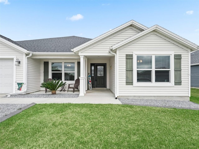 ranch-style house featuring a garage, roof with shingles, and a front yard