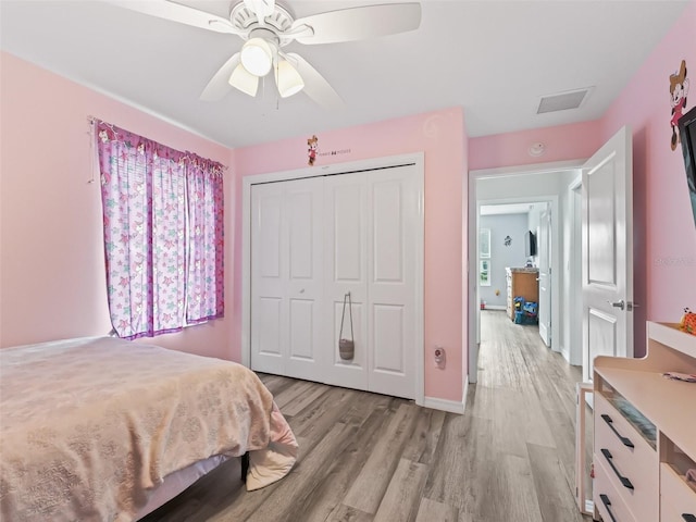 bedroom with light wood finished floors, visible vents, baseboards, a ceiling fan, and a closet