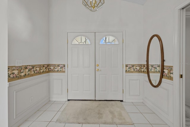 entryway with a wainscoted wall and light tile patterned flooring