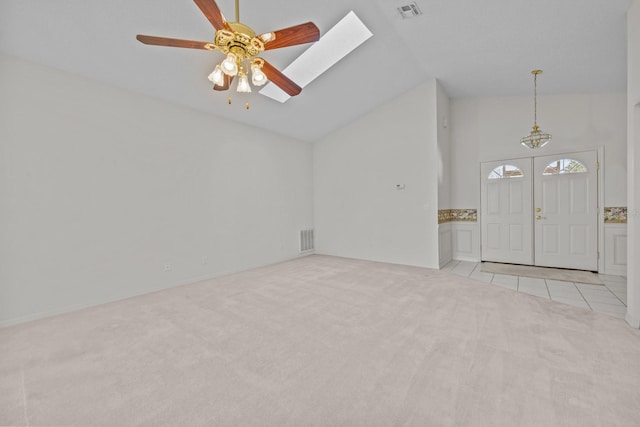 interior space with a ceiling fan, a skylight, visible vents, and tile patterned floors