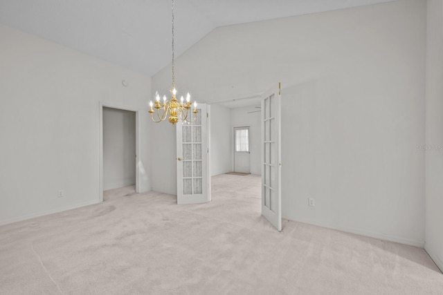 empty room with a chandelier, french doors, carpet flooring, and vaulted ceiling