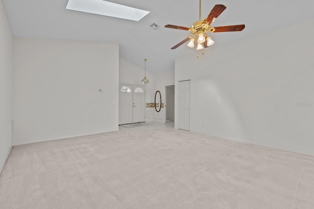 unfurnished living room featuring carpet, a skylight, visible vents, a ceiling fan, and high vaulted ceiling