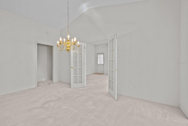 carpeted spare room with a chandelier, vaulted ceiling, and french doors