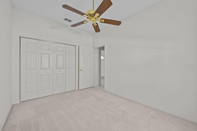 unfurnished bedroom with a closet, visible vents, a ceiling fan, light carpet, and vaulted ceiling