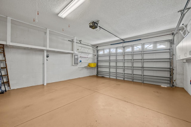 garage with a garage door opener, concrete block wall, and electric panel