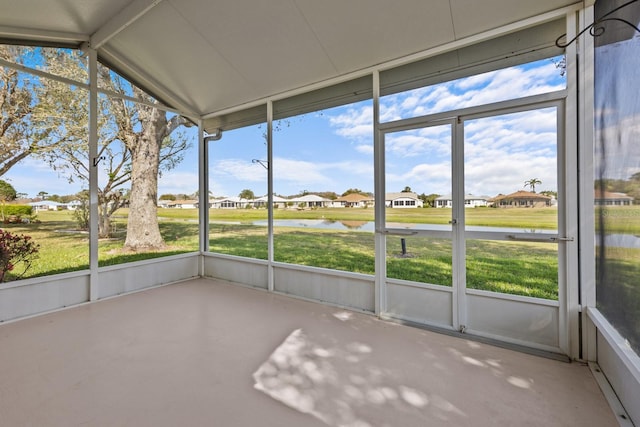 unfurnished sunroom featuring a water view, a residential view, and vaulted ceiling