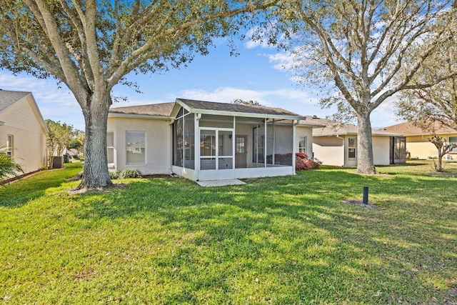 back of house with a sunroom, a yard, and stucco siding