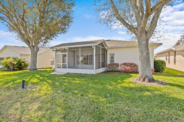 rear view of house with a lawn and a sunroom