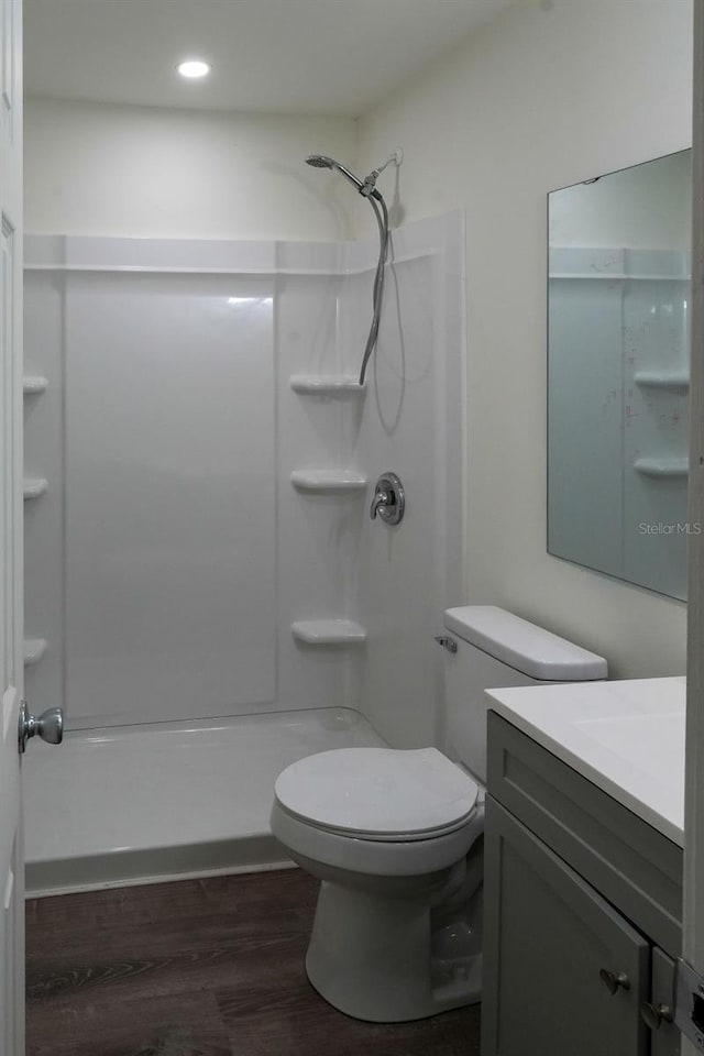 bathroom with toilet, vanity, hardwood / wood-style floors, and a shower