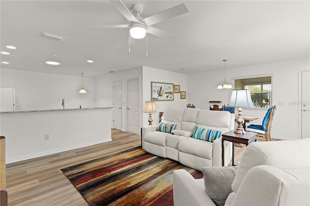 620 Vagabond St, The Villages, FL 32163 - living room with a textured ceiling, baseboards, wood finished floors, and ceiling fan with notable chandelier