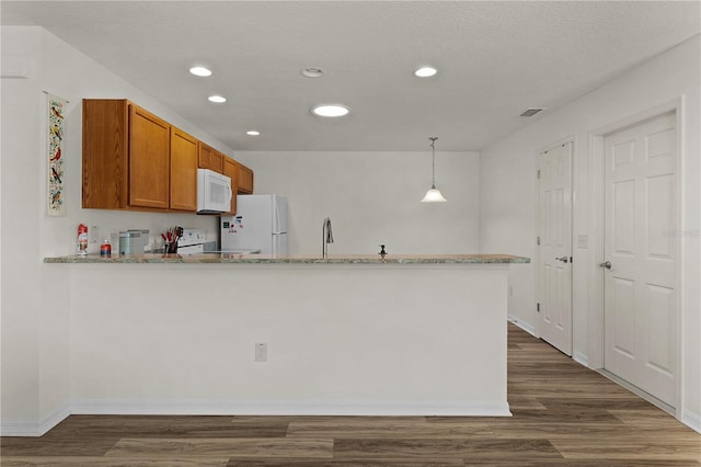 620 Vagabond St, The Villages, FL 32163 - kitchen featuring a peninsula, white appliances, brown cabinets, dark wood-style floors, and decorative light fixtures