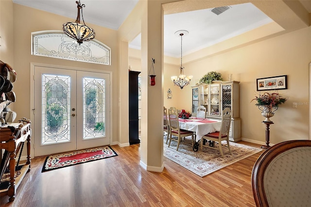 entrance foyer with french doors, a notable chandelier, baseboards, and wood finished floors