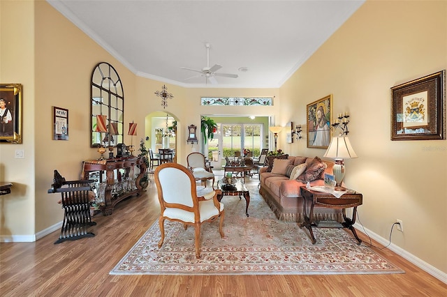 living area featuring baseboards, crown molding, arched walkways, and wood finished floors