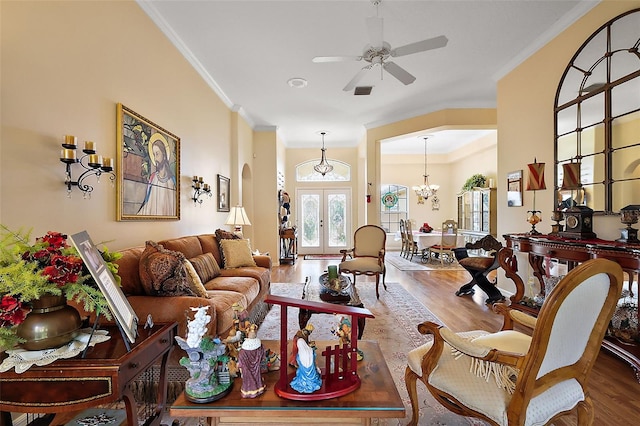 living area with ornamental molding, ceiling fan with notable chandelier, french doors, and wood finished floors