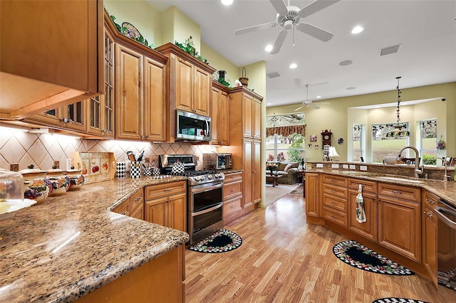 kitchen with visible vents, glass insert cabinets, brown cabinets, stainless steel appliances, and pendant lighting