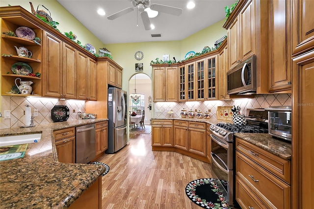 kitchen featuring light wood finished floors, open shelves, appliances with stainless steel finishes, and brown cabinetry