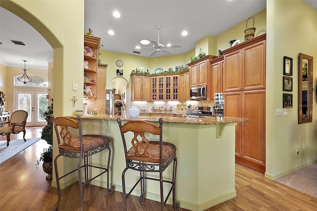 kitchen featuring appliances with stainless steel finishes, a kitchen breakfast bar, a peninsula, and light stone counters