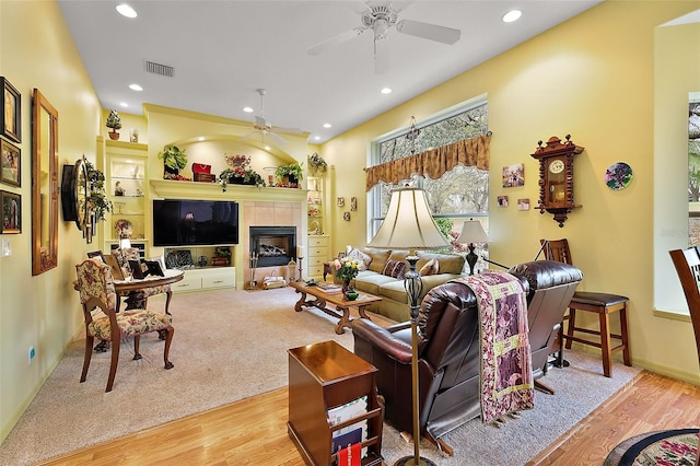 living room with ceiling fan, recessed lighting, visible vents, light wood-style floors, and a tiled fireplace