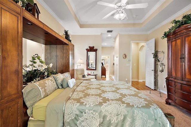 bedroom with visible vents, arched walkways, a raised ceiling, light colored carpet, and ornamental molding