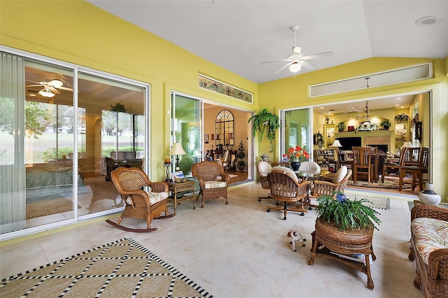 sunroom with lofted ceiling, a fireplace, and ceiling fan