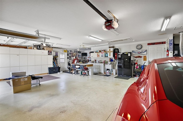 garage featuring a garage door opener, visible vents, and a workshop area