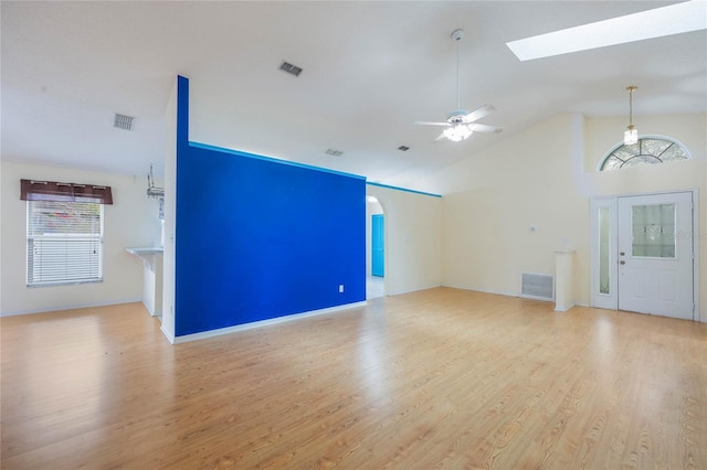 unfurnished living room with visible vents, arched walkways, and wood finished floors