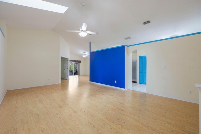 unfurnished room featuring arched walkways, ceiling fan, visible vents, and light wood-style floors