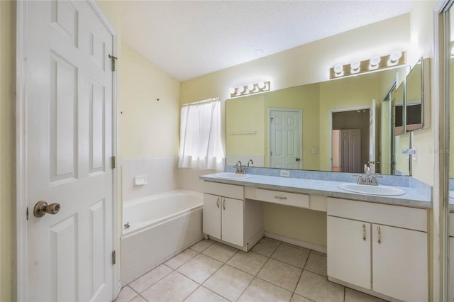 full bath featuring a garden tub, a textured ceiling, a sink, and tile patterned floors