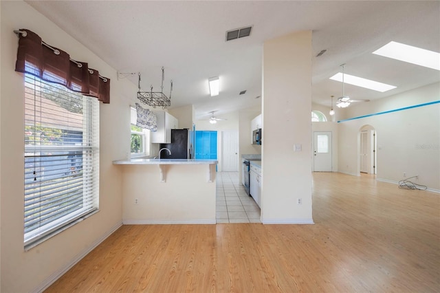 kitchen featuring a peninsula, appliances with stainless steel finishes, visible vents, and a ceiling fan