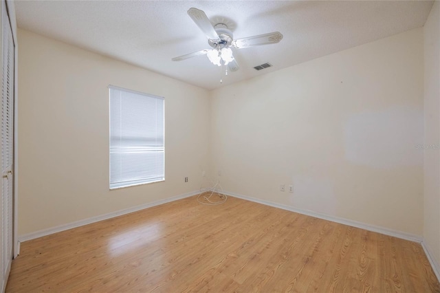 spare room with baseboards, a ceiling fan, visible vents, and light wood-style floors