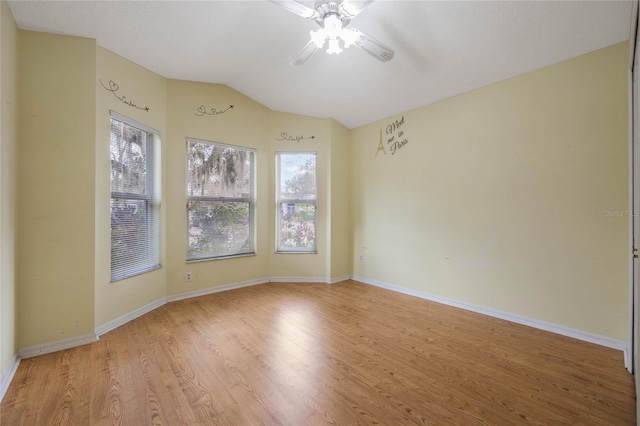 empty room with vaulted ceiling, ceiling fan, light wood-style floors, and a healthy amount of sunlight