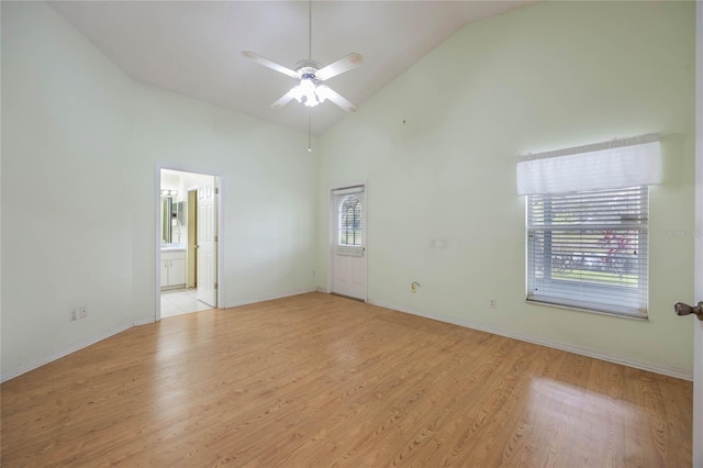 empty room with light wood-style flooring, high vaulted ceiling, ceiling fan, and baseboards