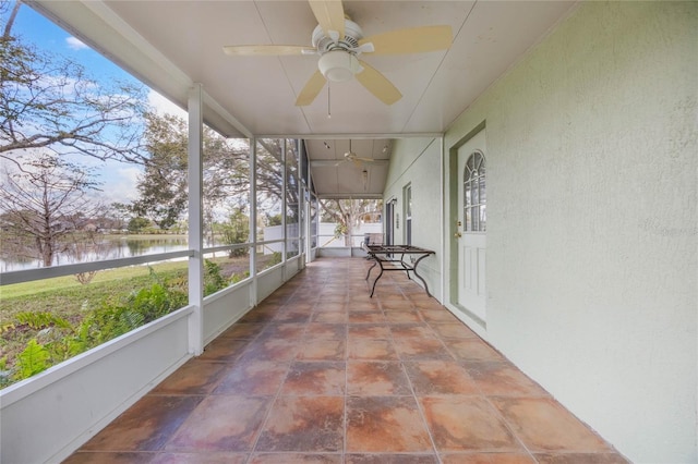 unfurnished sunroom featuring a water view, a wealth of natural light, and a ceiling fan