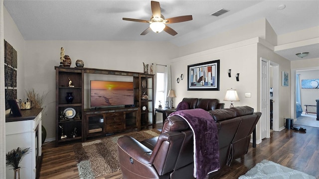 living area featuring baseboards, visible vents, a ceiling fan, dark wood-style flooring, and vaulted ceiling