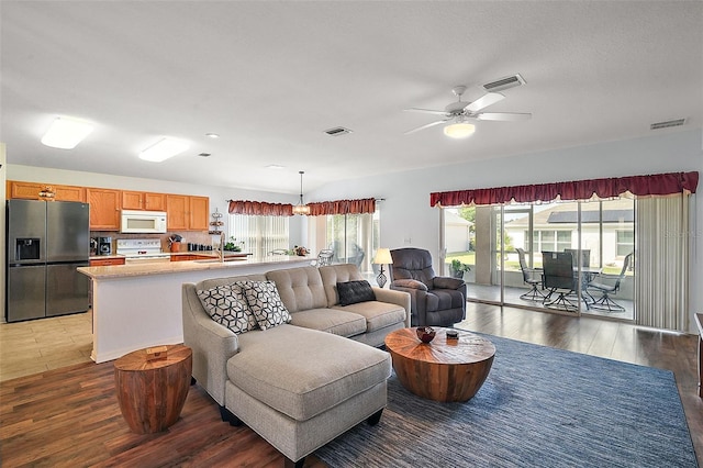 living area with ceiling fan, visible vents, and dark wood-style flooring