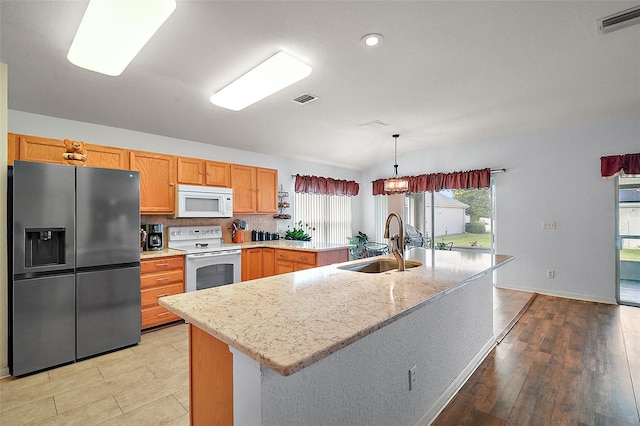 kitchen with white appliances, visible vents, a sink, and decorative light fixtures