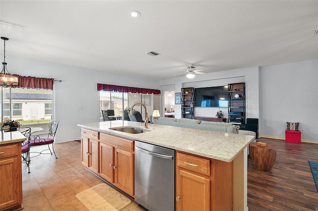 kitchen with decorative light fixtures, a sink, visible vents, dishwasher, and a center island with sink