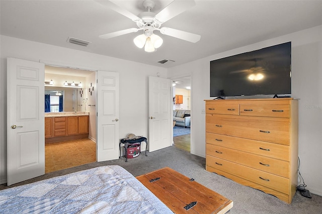 carpeted bedroom with connected bathroom, visible vents, and a ceiling fan