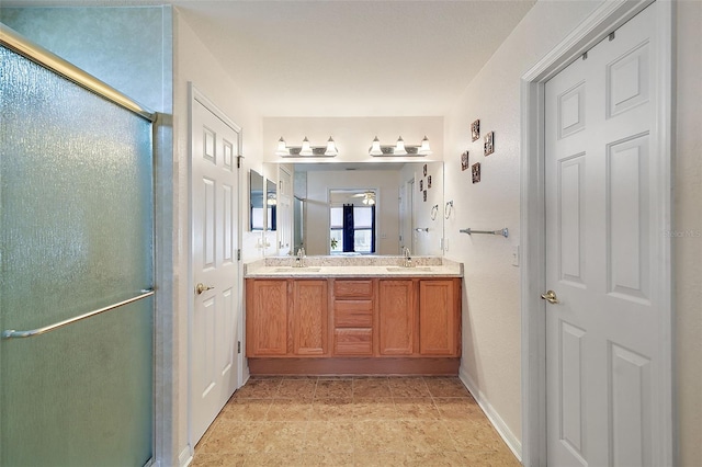 bathroom featuring double vanity, a shower stall, and a sink