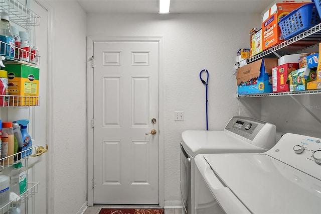 laundry area with laundry area, washing machine and dryer, and baseboards