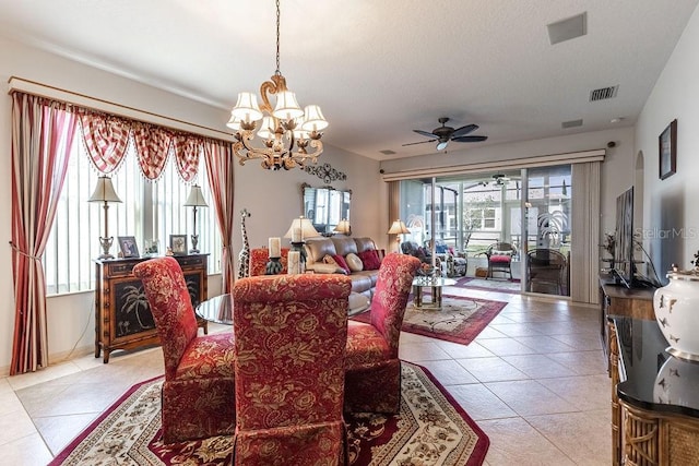 tiled dining room with ceiling fan with notable chandelier